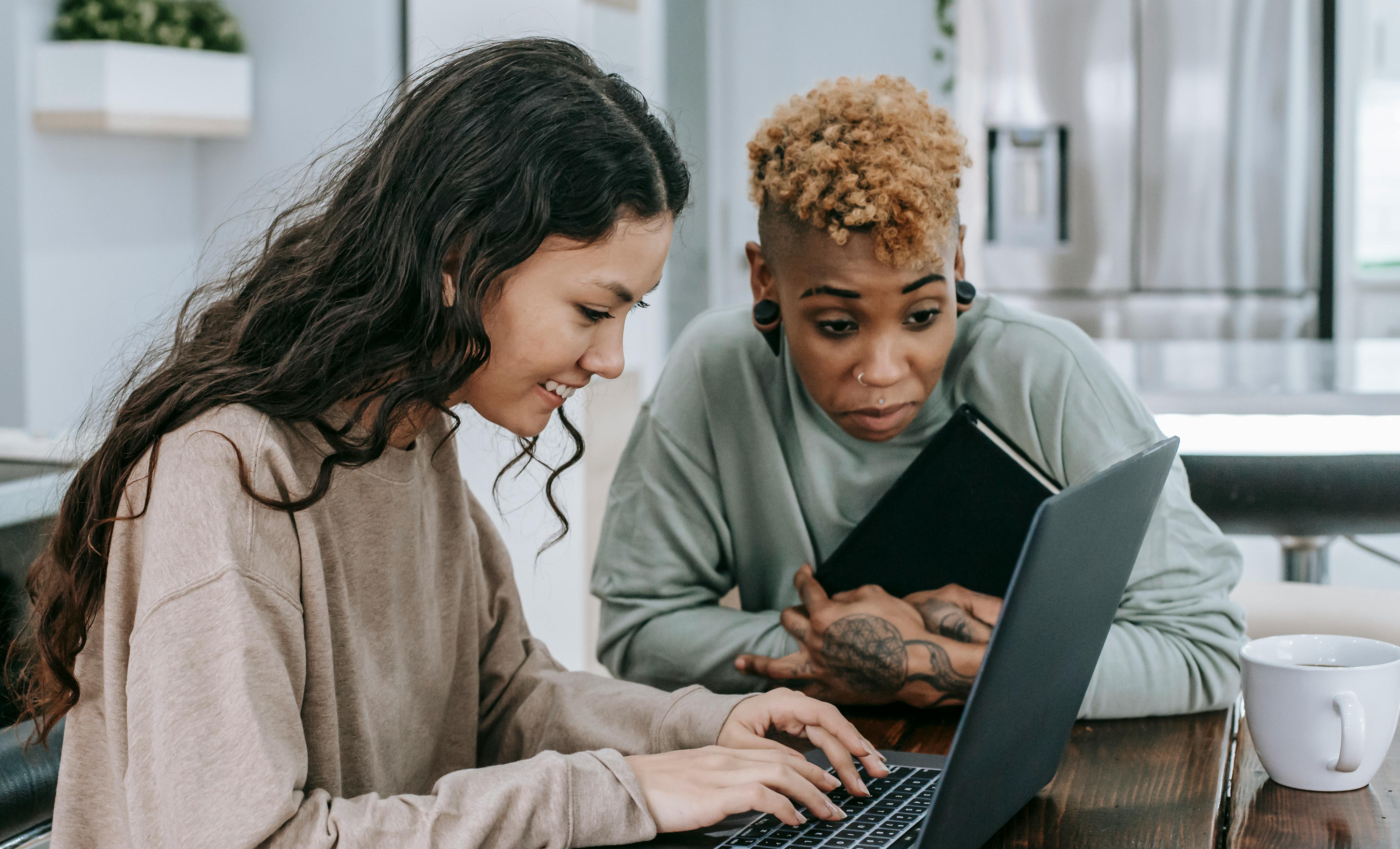 Two femme professionals working together on a laptop